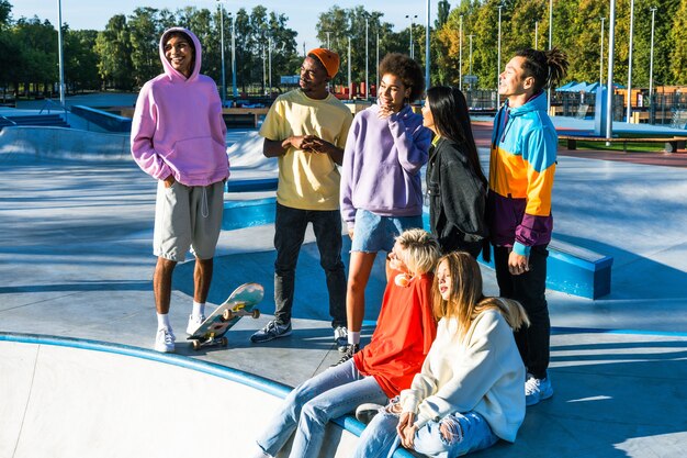 Multiculturele groep jonge vrienden die buiten een band hebben en plezier hebben - Stijlvolle coole tieners die samenkomen in het stedelijke skatepark