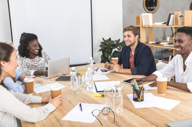 Multiculturele lachende zakenmensen bespreken bedrijfsstrategie tijdens seminar op kantoor