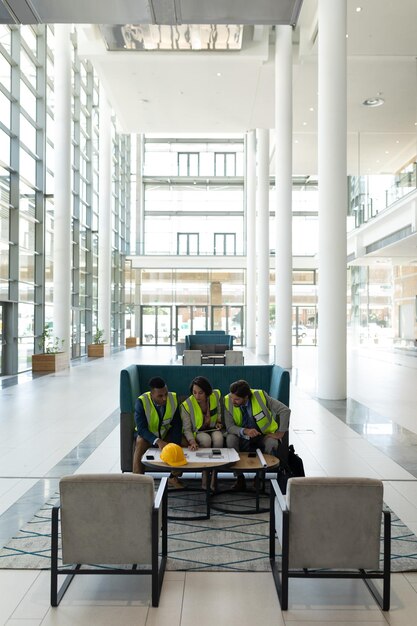 Photo multiethnic business architect sitting and discussing over the blue print in lobby at office