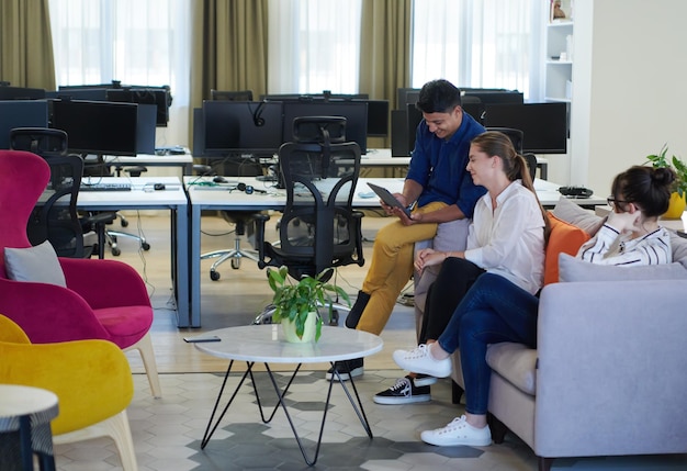 multiethnic business people Indian man with a female colleague working together on tablet computer in relaxation area of modern startup office