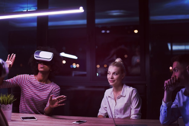 Photo multiethnic business team using virtual reality headset in night office meeting  developers meeting with virtual reality simulator around table in creative office.