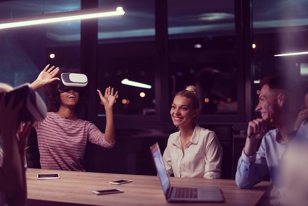 Multiethnic Business team using virtual reality headset in night office meeting  Developers meeting with virtual reality simulator around table in creative office.