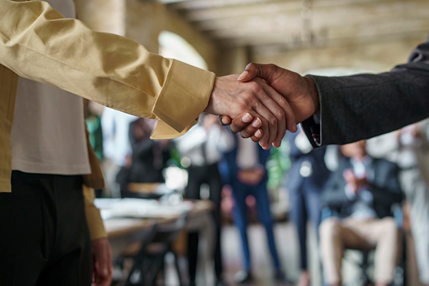 Multiethnic businesswoman shaking hands closeup with blurred colleagues