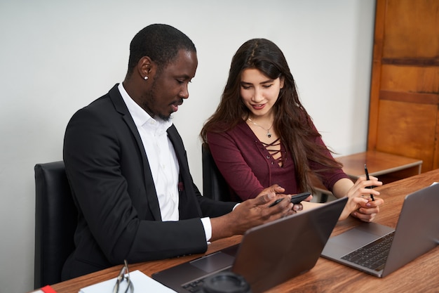 Multiethnic Colleagues Use Cellphones and Try Smartphone Applications In Office