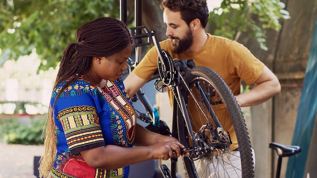 写真 多民族の夫婦が損傷した自転車を修理する