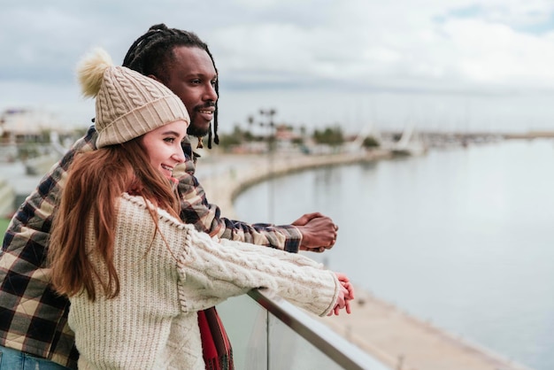 A multiethnic couple of friends contemplating the view of the harbor