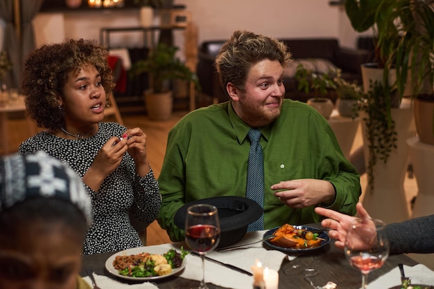 Multiethnic couple talking to their friends during meeting at dinner party