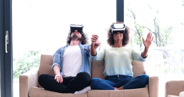 Multiethnic Couple using virtual reality headset in living room at home  people playing game with new trends technology