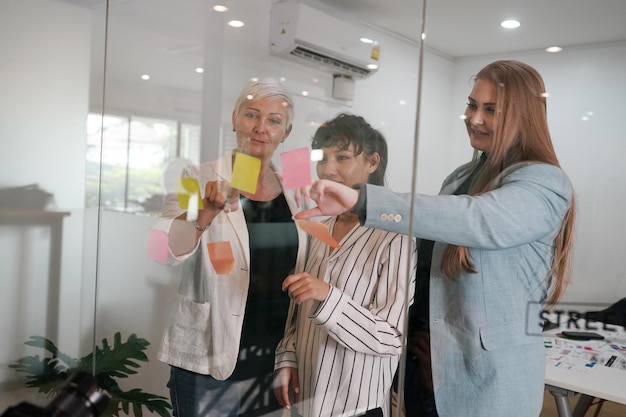 Multiethnic coworkers discussing project in office looking on sticky notes