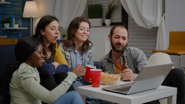 Photo multiethnic friends sitting on couch having online videocall meeting