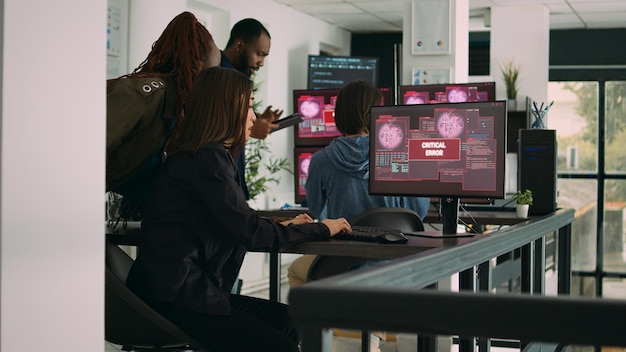 Photo multiethnic group of app developers reading critical errors on multiple monitors in it agency, being hacked. working with artificial intelligence code and server database to stop program hacking.