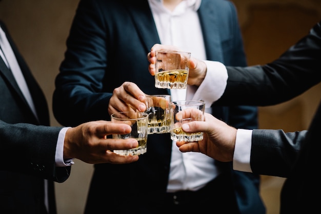 Multiethnic group of businessmen spending time together drinking whiskey and smoking