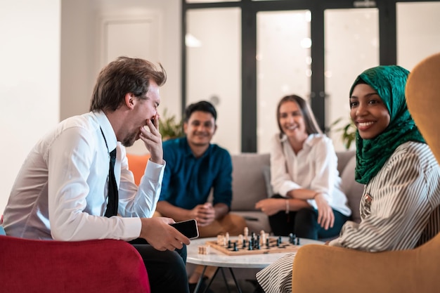 Multiethnic group of businesspeople playing chess while having\
a break in relaxation area at modern startup office. high-quality\
photo