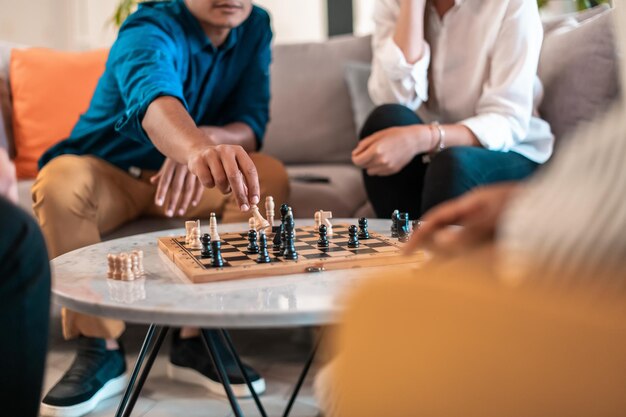 Multiethnic group of businesspeople playing chess while having\
a break in relaxation area at modern startup office. selective\
focus. high-quality photo