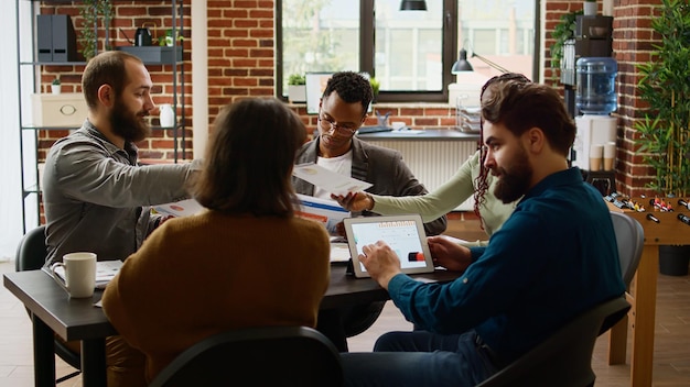 Multiethnic group of colleagues brainstorming ideas to plan\
report, analyzing research data on documents to do paperwork and\
project. people working on startup presentation with analysis.