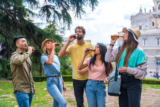 市内の公園でビールを飲みながらパーティーをする多民族の友人のグループ 冷たいビールを飲む友人