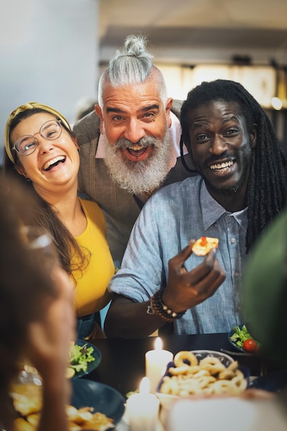 Multiethnic group of friends smiling looking at camera while theyre dining together at home