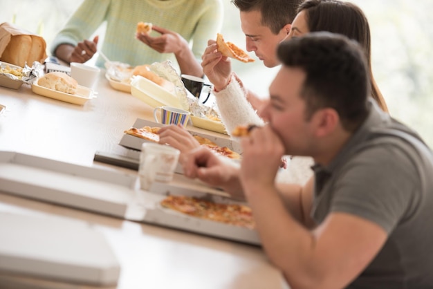 食べ物やソーダの飲み物と一緒に時間を過ごし、家で食べるという幸せな友人の多民族グループコンセプト