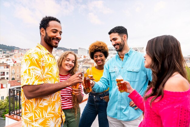 Multiethnic group of happy young friends having dinner barbecue party on rooftop at home