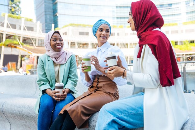 Multiethnic group of muslim girls wearing casual clothes and traditional hijab bonding and having fun outdoors - 3 arabic young girls