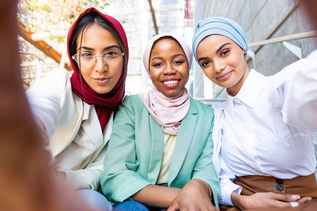 multiethnic group of muslim girls wearing casual clothes and traditional hijab bonding outdoors