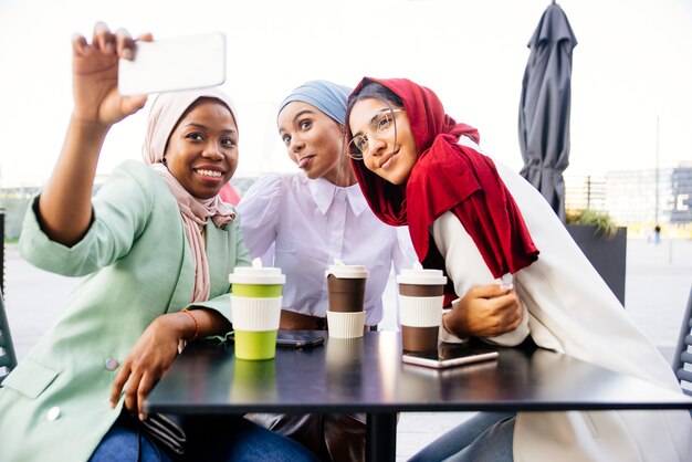 multiethnic group of muslim girls wearing casual clothes and traditional hijab bonding outdoors