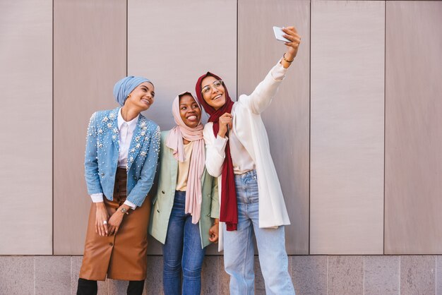 Multiethnic group of muslim girls wearing casual clothes and traditional hijab bonding