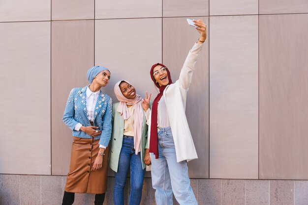 multiethnic group of muslim girls wearing casual clothes and traditional hijab bonding