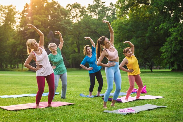 Фото Многонациональная группа пожилых женщин, тренирующихся в парке с инструктором по фитнесу - активные пожилые люди, занимающиеся спортом на природе