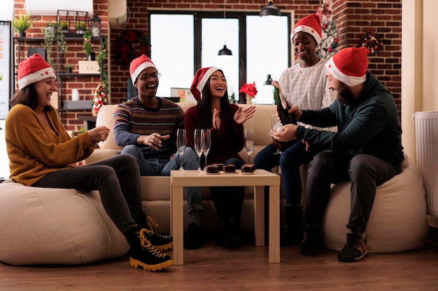 クリスマス パーティーのお祭りで冬休みを祝うためにワインのグラスを飲む人々 の多民族グループ。お祝いのオフィスでのクリスマス イベントで楽しんでいるアルコール飲料との同僚。