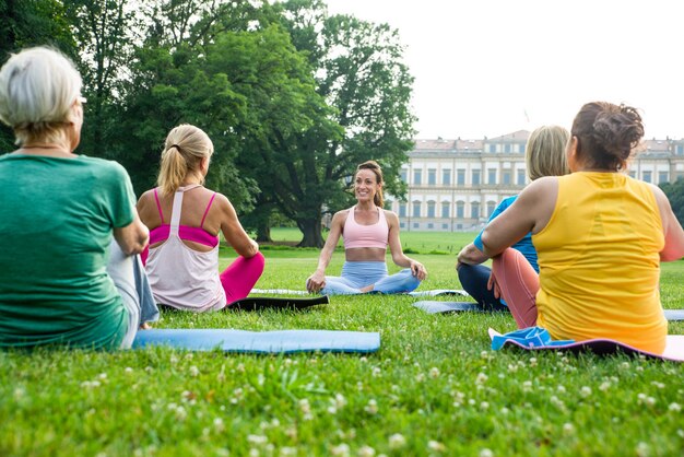 Multiethnic group of senior women training at park with fitness instructor - Active elderly people doing sport in the nature