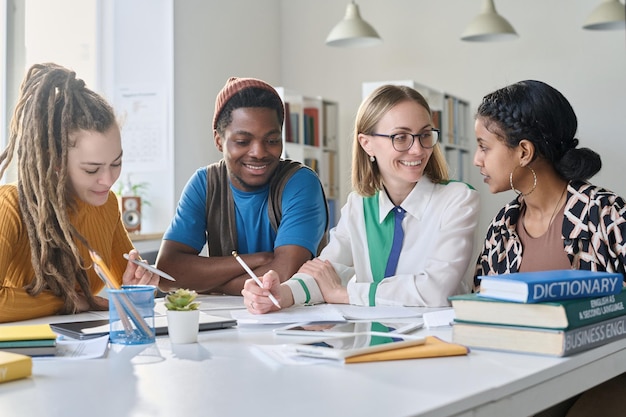 Multiethnic group of students talking to teacher during lesson in class