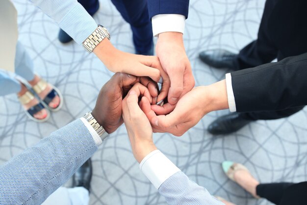 Foto gruppo multietnico di giovani che mettono le mani uno sopra l'altro. chiuda sull'immagine di giovani uomini d'affari che fanno una pila di mani.