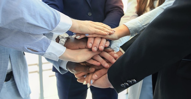 Multiethnic group of young people putting their hands on top of each other