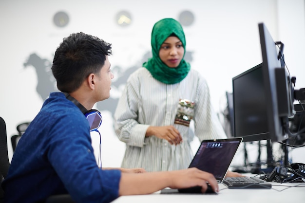 Multiethnic startup business team Arabian woman wearing a hijab on meeting in modern open plan office interior brainstorming, working on laptop and desktop computer