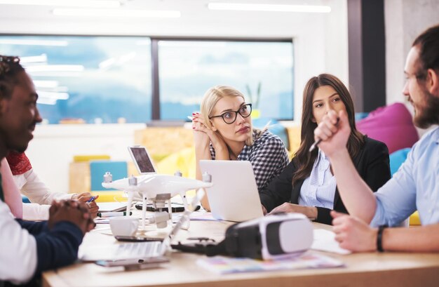 multiethnic startup business team discussing new business plan,working on laptop and tablet computer while learning about drone technology for new business advancement