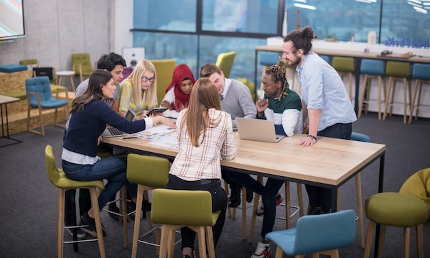 Multiethnic startup business team on meeting in modern bright office interior brainstorming, working on laptop and tablet computer