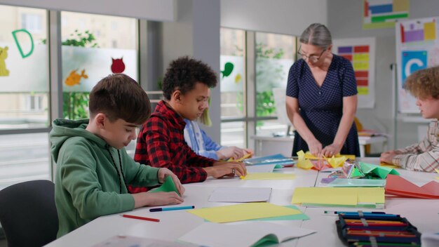 Multiethnic students have origami lesson with mature teacher at school