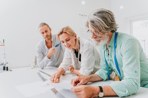 Team multietnico di stilisti al lavoro in un laboratorio di start-up di abbigliamento - gruppo multietnico di stilisti, stilisti e sarti al lavoro su una nuova collezione