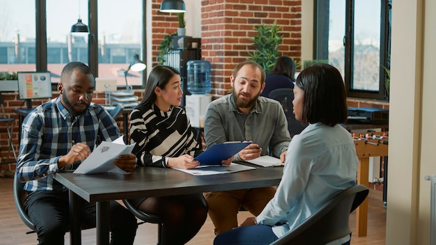 Multiethnic team of HR people interviewing job candidate, analyzing cv resume and talking about recruitment. Woman meeting with group of businesspeople to discuss about executive job.