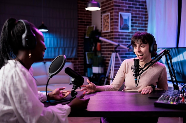 Multiethnic team of women meeting in studio to film podcast\
chat together, creating content for social media channel. female\
influencers using professional recording equipment at station.