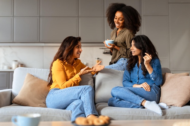 Foto donne multietniche condividono storie sedute con una tazza di tè in casa