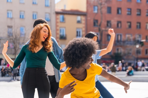 Giovani amici multietnici che ballano in una piazza cittadina godendosi la festa con gli amici
