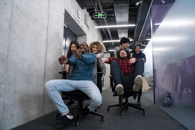 multiethnics startup business team of software developers having fun while racing on office chairs,excited diverse employees laughing enjoying funny activity at work break, creative friendly workers p