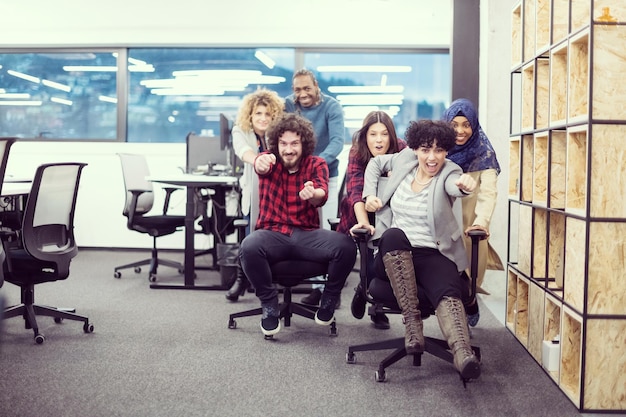 multiethnics startup business team of software developers having fun while racing on office chairs,excited diverse employees laughing enjoying funny activity at work break, creative friendly workers p