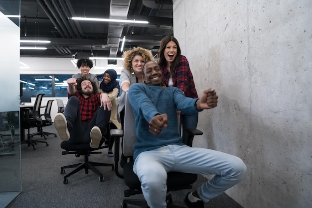 multiethnics startup business team of software developers having fun while racing on office chairs,excited diverse employees laughing enjoying funny activity at work break, creative friendly workers p