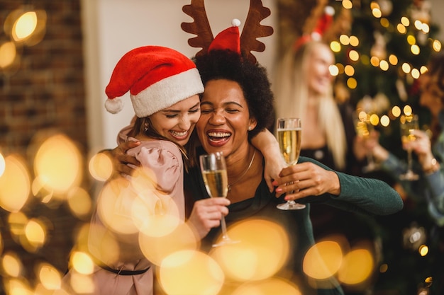 Мультиэтнические подруги собрались дома, чтобы отпраздновать Рождество или Новый год. делая тост с шампанским.