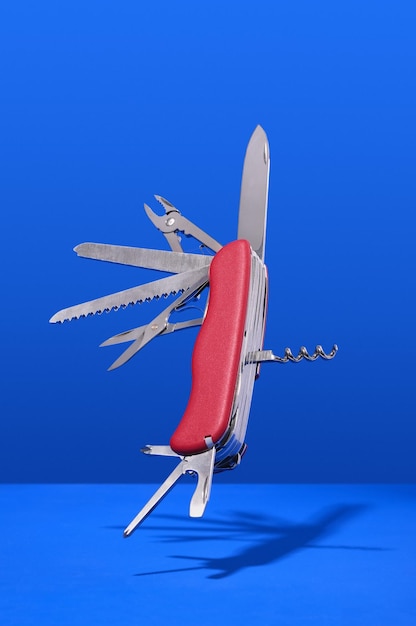 Multifunctional folding Swiss knife red color on blue background Inspiration hand work