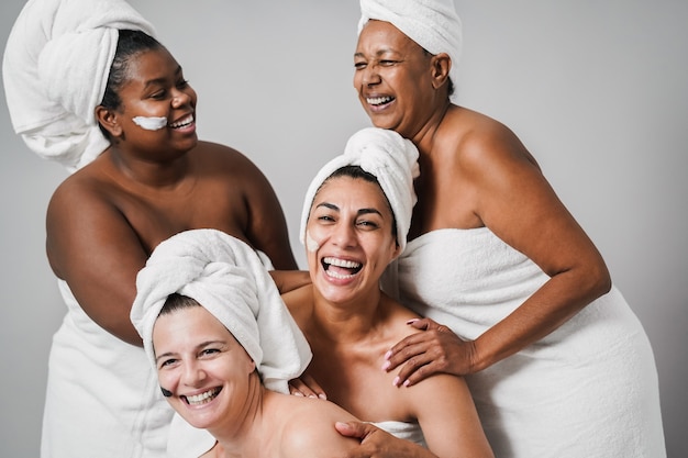 Multigeneration women with diverse skin and body laughing together while wearing body towels - Focus on center female face