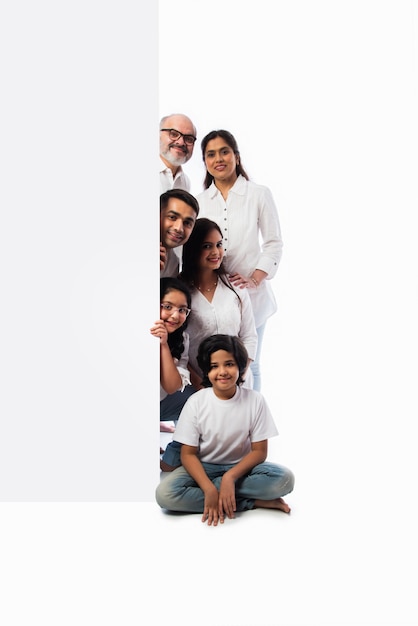 Multigenerational Indian asian family with white board, pointing or presenting empty white placard